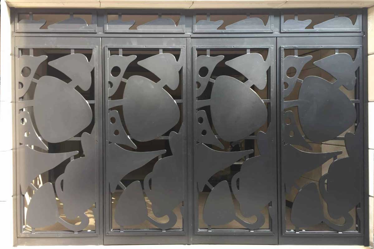 Decorative metal gate with stylized fish silhouettes overlapping in dark panels.